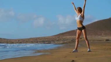 Yoga kadın çalışma dışarı ve dışında kumsalda güneş doğarken rahatlatıcı Plajı'nda teşkil etmektedir. Kadın yoga-kız çalışma eğitim sakin okyanus manzara içinde dışarı. Ağır çekim Steadicam