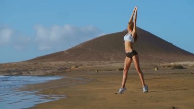 Yoga kadın çalışma dışarı ve dışında kumsalda güneş doğarken rahatlatıcı Plajı'nda teşkil etmektedir. Kadın yoga-kız çalışma eğitim sakin okyanus manzara içinde dışarı. Ağır çekim Steadicam