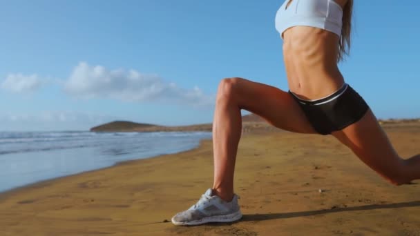 Жінка робить ногу розтягнутою. Фітнес дівчина розтягує ноги на тренуваннях на пляжі. СЛАДНІЙ СКАДІКАМ — стокове відео