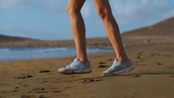 白いスニーカーのビーチ、美しい白い砂の上を歩く女性のクローズ アップ ショット。スローモーション ステディカム — ストック動画