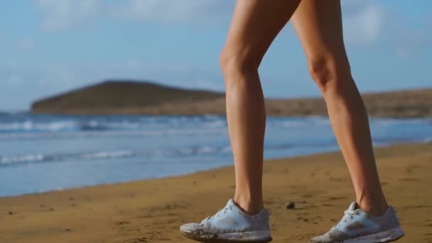 Nahaufnahme einer Frau in weißen Turnschuhen, die am Strand mit schönem weißen Sand spazieren geht. Schwebestativ in Zeitlupe — Stockvideo