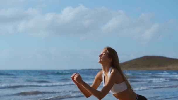 Deportiva usando ropa deportiva haciendo sentadillas ejercitarse al aire libre. Fitness Mujer haciendo ejercicio en la playa al atardecer. Atlética mujer joven se dedica a los deportes al aire libre . — Vídeos de Stock