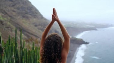 Genç kadının yoga meditasyon Lotus bulunduğu bir dağın tepesinde bir kayaya oturan okyanusa bakan bir adada dağlarda yapması