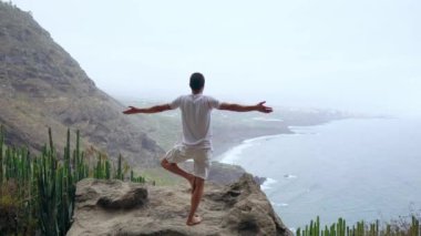 Uygun genç adam ocean için dağ Güneş selamlama yoga uygulamaları. Genç zevk meditasyon ve yoga adam. Fitness, spor, insanlar ve yaşam tarzı kavramı - yoga egzersizleri yapma genç adam.