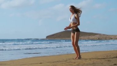 Kız spor şort ve tişört ile ağız kavgası atlar gerçekleştirir ve Kanarya Adaları'nda Okyanusu yakınlarındaki sahilde gürlemesi. Sağlıklı yaşam ve fitness tatil. Güzel ve sağlıklı vücut