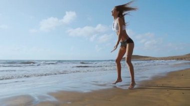 Kız spor şort ve tişört ile ağız kavgası atlar gerçekleştirir ve Kanarya Adaları'nda Okyanusu yakınlarındaki sahilde gürlemesi. Sağlıklı yaşam ve fitness tatil. Güzel ve sağlıklı vücut