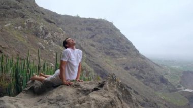 Köpek poz okyanus manzarasına sahip bir uçurumun kenarında duran adam adalar yoga yolculuğu sırasında deniz havada nefes