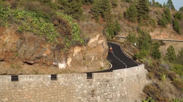 Un homme en t-shirt jaune sur une route de sport balades à vélo sur la route située en haute montagne — Video