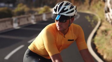 Sarı bir tişört ve dağ yolunda mesafe ayakta içine kask bir bisiklet üzerinde oturan bir adam