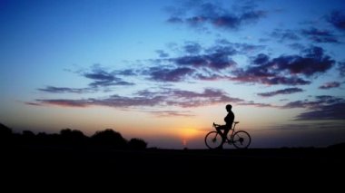 Akşam ışığı şaşırtıcı gökyüzüne bisikletini kaldırma ile kutlayan ilk Mountainbiker