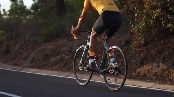 Un hombre en una carretera deportiva paseos en bicicleta en la carretera situada en lo alto de las montañas — Vídeos de Stock