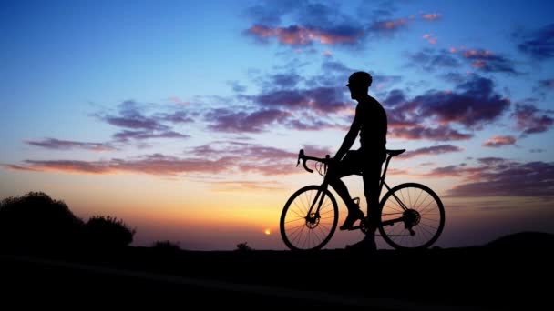 Silueta kolo Rider na skále při západu slunce