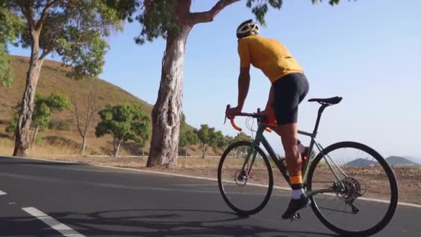 Bir adam yolda yol bisikleti rides bir spor yüksek dağlarda bulunan. ağır çekimde. — Stok video