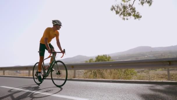 Een man op een racefiets op de weg rijdt sport ligt hoog in de bergen. in slow motion. — Stockvideo