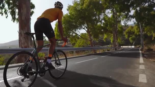 Un hombre en una bicicleta de carretera deportiva pasea por la carretera situada en lo alto de las montañas. en cámara lenta . — Vídeos de Stock