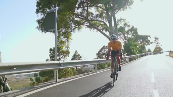 Un uomo su una bici da strada sportiva viaggia sulla strada situata in alto in montagna. al rallentatore . — Video Stock