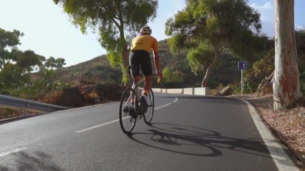 Muž na je sportovní silniční kolo jede na silnici nachází se vysoko v horách. v pomalém pohybu. — Stock video
