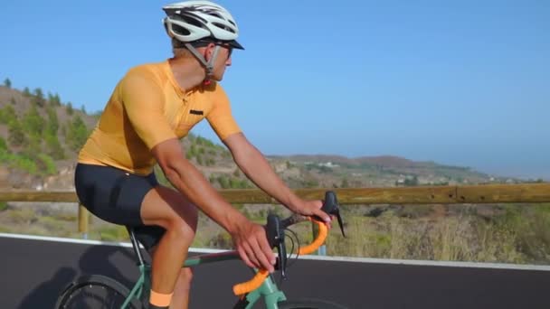 Mountain bike cyclist riding uphill along a road. Rear view. Summer day. slow motion — Stock Footage Mountain bike cyclist riding uphill along a road. Rear view. Summer day. slow motion Video Clip