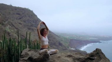 Bir dağın tepesinde oturan bir kadın meditasyon ve elleri Maha sakal grubunun bir jest yapar. Yeşil dağlar ve okyanus karşı