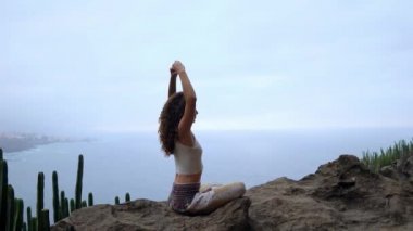 Bir dağın tepesinde oturan bir kadın meditasyon ve elleri Maha sakal grubunun bir jest yapar. Yeşil dağlar ve okyanus karşı