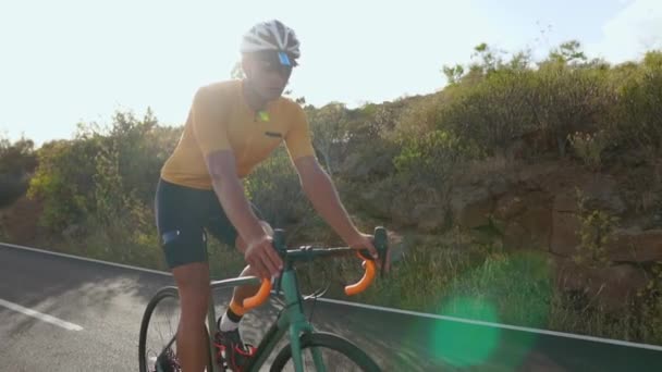 Ciclista andando de bicicleta em uma estrada aberta para o pôr do sol — Vídeo de Stock