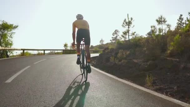 Ciclista montando una bicicleta en un camino abierto a la puesta del sol — Vídeos de Stock