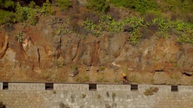 Bir dağ yolu tırmanma bir erkek bisikletçi video çekim izleme. Güneşli bir günde bir tepelik otoyol yolda Bisiklete binme eğitim yapan erkek.