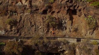Bir dağ yolu tırmanma bir erkek bisikletçi video çekim izleme. Güneşli bir günde bir tepelik otoyol yolda Bisiklete binme eğitim yapan erkek.