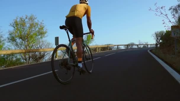 Un uomo va in bici per strada. Sport e vita attiva concetto tempo di tramonto. Un uomo che va in bicicletta in un parco. Cielo blu con raggio di sole arancione sul corpo del ciclista . — Video Stock