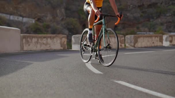 Gran ángulo de seguimiento de tiro de un atleta masculino en forma montar en bicicleta en el largo camino plano en el campo. Hombre ciclismo en carretera plana carretera . — Vídeos de Stock