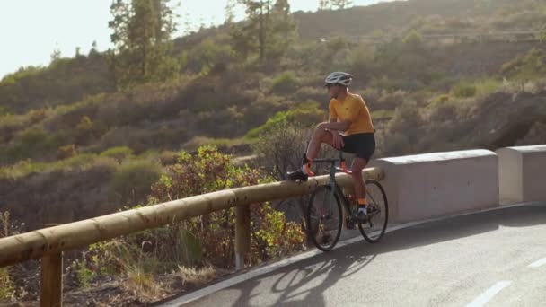Prise de vue grand angle d'un athlète masculin en forme faisant du vélo sur une longue route plate à la campagne. Homme vélo sur route plate . — Video