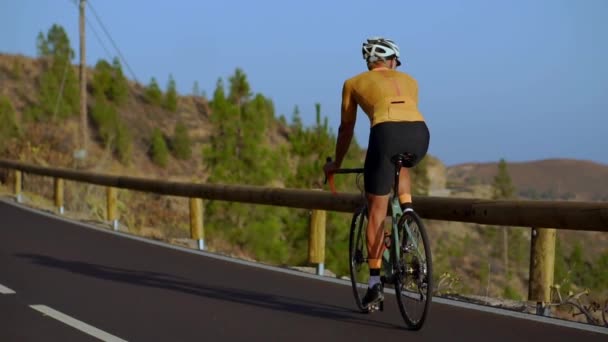 Groothoek tracking shot van een fit mannelijke atleet fietsten op lange vlakke weg in platteland. Fietsen op vlakke snelweg weg man. — Stockvideo