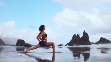 Mutlu genç kadın batımında sahilde Yoga uygulamak. Sağlıklı aktif yaşam tarzı kavramı. Ağır çekim