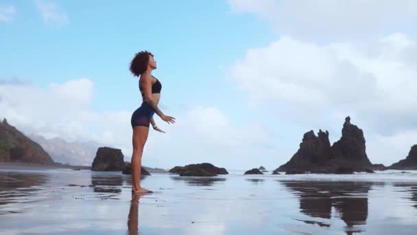 Schöne athletische Mädchen in Sportbekleidung auf dem Ozean nach Ebbe machen Übungen zum Aufwärmen und Muskelaufbau. das Konzept eines gesunden Lebensstils. Yoga — Stockvideo