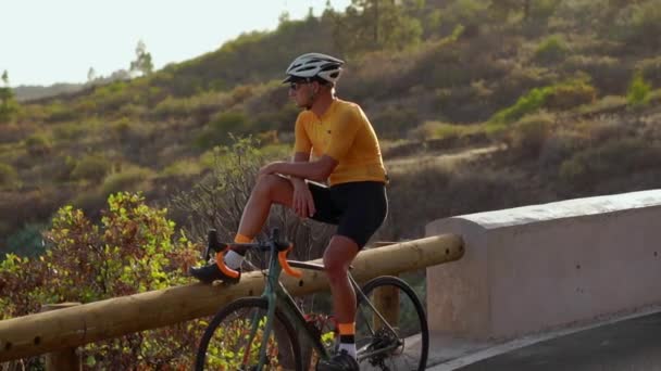 Чоловік-велосипедист відпочиває після прибуття і захоплюється видом на гори — стокове відео