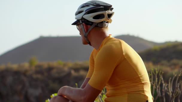 Man cyclist resting after arrival and admiring the view of the mountains — Stock Footage Man cyclist resting after arrival and admiring the view of the mountains Stock Video