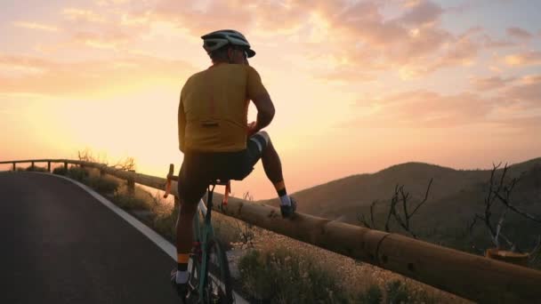 Een wielrenner in een helm en sport apparatuur staan aan de rand van de berg neemt een prachtig uitzicht op de mobiele telefoon — Stockvideo