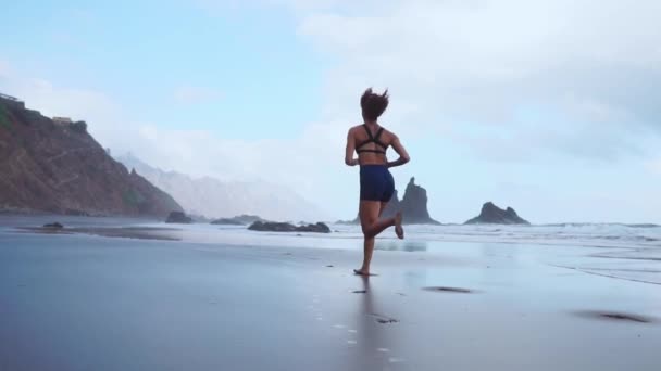 Vrouw met zwart vulkanisch zand op de Canarische eilanden op de achtergrond van bevroren magma. Het concept van een gezonde levensstijl. Slow motion. — Stockvideo