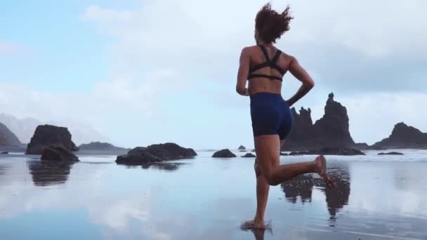 Chica deportiva descalza con cuerpo delgado corriendo a lo largo del mar surf junto a la piscina de agua para mantenerse en forma y la salud. Fondo de playa con cielo azul. Mujer fitness, actividad deportiva de jogging en vacaciones familiares de verano . — Vídeos de Stock