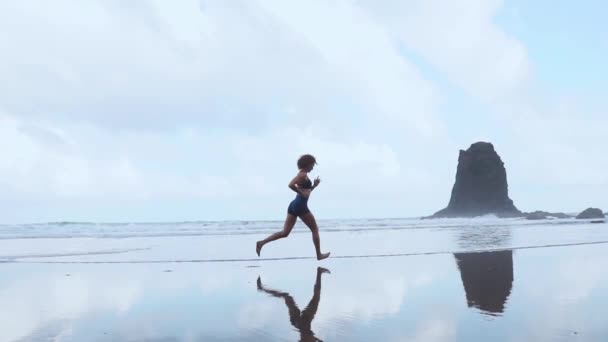 Barfuß sportliches Mädchen mit schlankem Körper, das entlang der Brandung am Wasserpool läuft, um fit und gesund zu bleiben. Strand Hintergrund mit blauem Himmel. Frauenfitness, Jogging-Sport im Sommer Familienurlaub. — Stockvideo