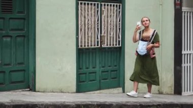 Anne Bebek bir askı içinde dar eski sokak aşağı gelip ona yolculuk bir cep telefonu hakkında video sosyal ağlar için vuruyor