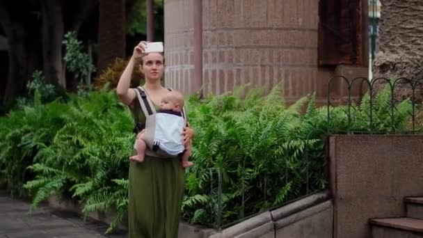 Eine Frau mit Baby reist auf der Insel, ein Kind sitzt im Tragetuch. — Stockvideo