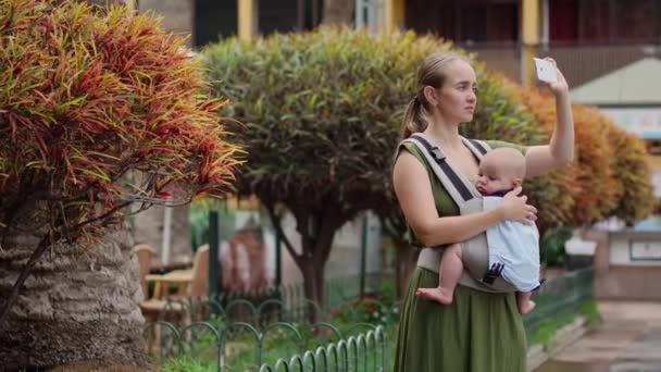 年轻的母亲与智能手机和婴儿旅行. — 图库视频影像