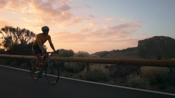 Man cyklist i gul t-shirt rider en mountainbike i solnedgången på motorvägen — Stockvideo