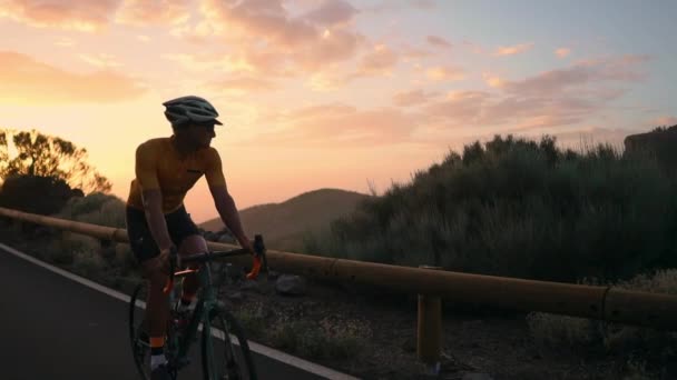 Uomo ciclista in t-shirt gialla guida di una mountain bike al tramonto in autostrada — Video Stock