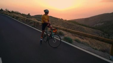 Gün batımını izlemek dağlarda sarı tişört adam bisikletçi. Iron man bir egzersiz yaptıktan sonra dinlenme