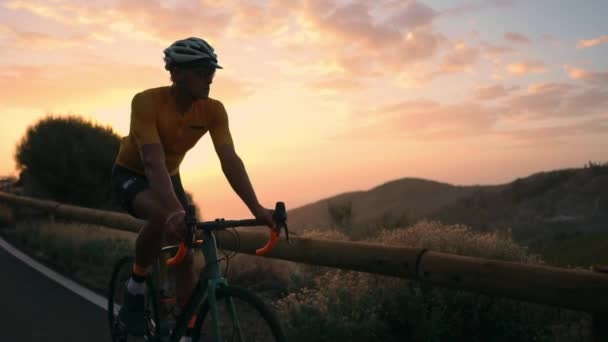 El atleta en una bicicleta va desde una roca en una serpentina de montaña mirando una hermosa vista de la isla. El concepto de un estilo de vida saludable — Vídeo de stock