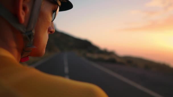 O rosto de homem, o ciclista de camisa amarela nas montanhas olhando para o pôr do sol. Descansando depois de um treino, homem de ferro — Vídeo de Stock