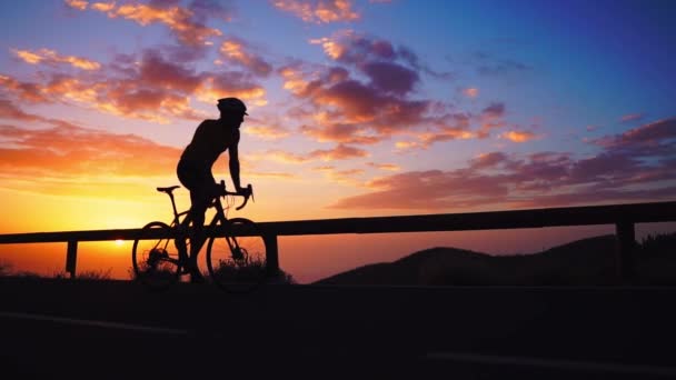 Silhouet van een fietser bij zonsondergang in de bergen — Stockvideo