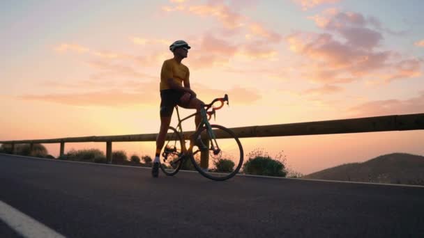 Un turista in bicicletta ammira il tramonto dalla cima della montagna — Video Stock